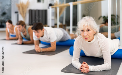 Group of sports people doing exercises with roller on yoga mats