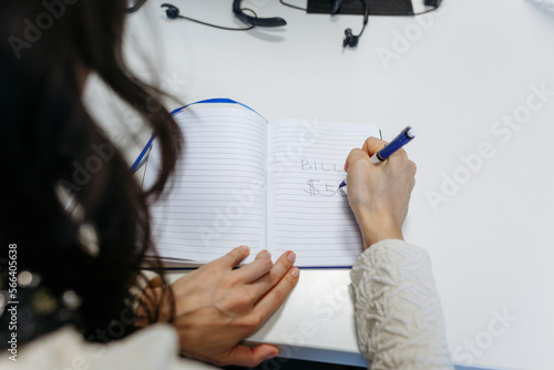 view on woman hands writing down expences on notebook photo