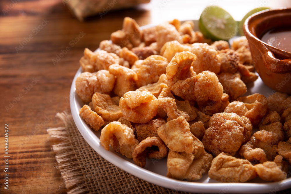 Chicharrones. Deep fried pork rinds, crispy pork skin pieces, traditional mexican ingredient or snack served with lemon juice and red hot chili sauce. Chicharrones. Deep fried pork rinds, crispy pork skin pieces, traditional mexican ingredient or snack served with lemon juice and red hot chili sauce.