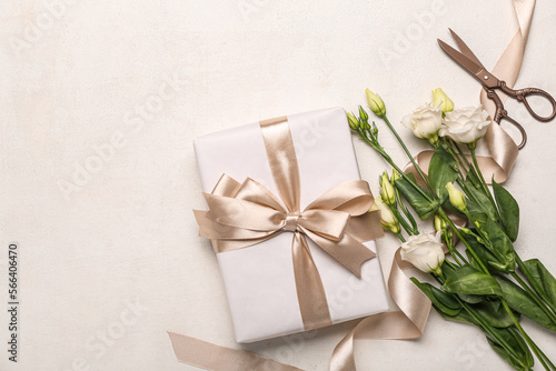 Gift box, beautiful eustoma flowers and scissors on light background. Women's Day celebration © Pixel-Shot