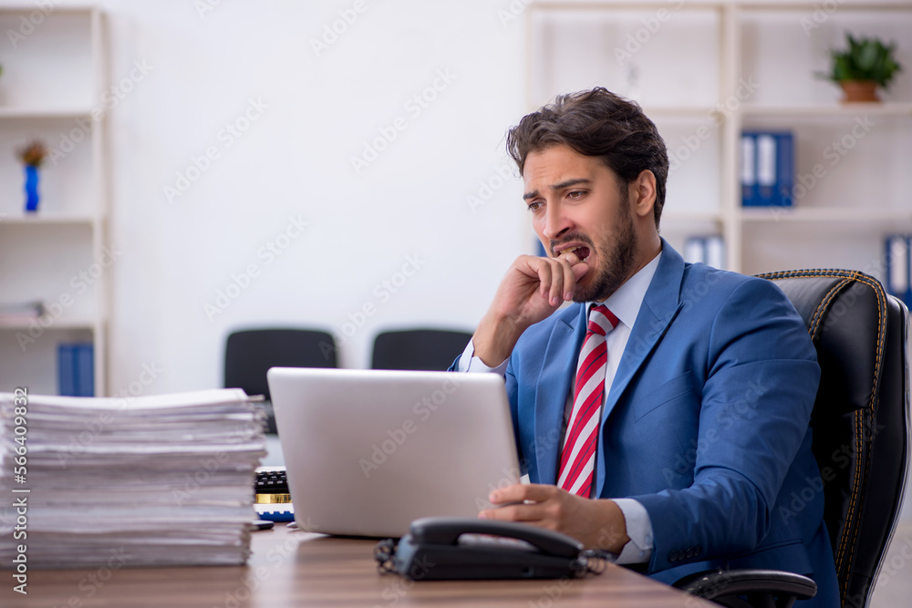 Young male employee and too much work in the office Young male employee and too much work in the office