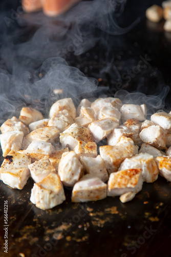 A closeup view of chopped chicken breast on the griddle.