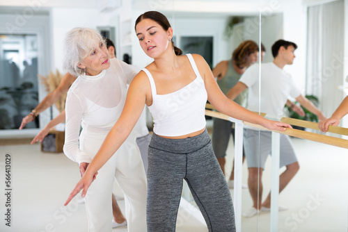 Senior woman choreographer and group of adult dancers practice ballet moves in classical dance school. © JackF