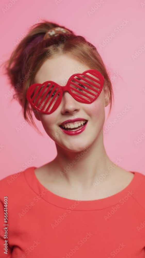 Vertical video. Valentines day party, Gen Z. Funny girl portrait wearing heart shaped eyeglasses. Vertical video. Valentines day party, Gen Z. Funny girl portrait wearing heart shaped eyeglasses.
