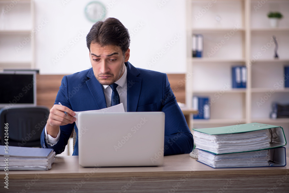 Young male employee and too much work in the office Young male employee and too much work in the office