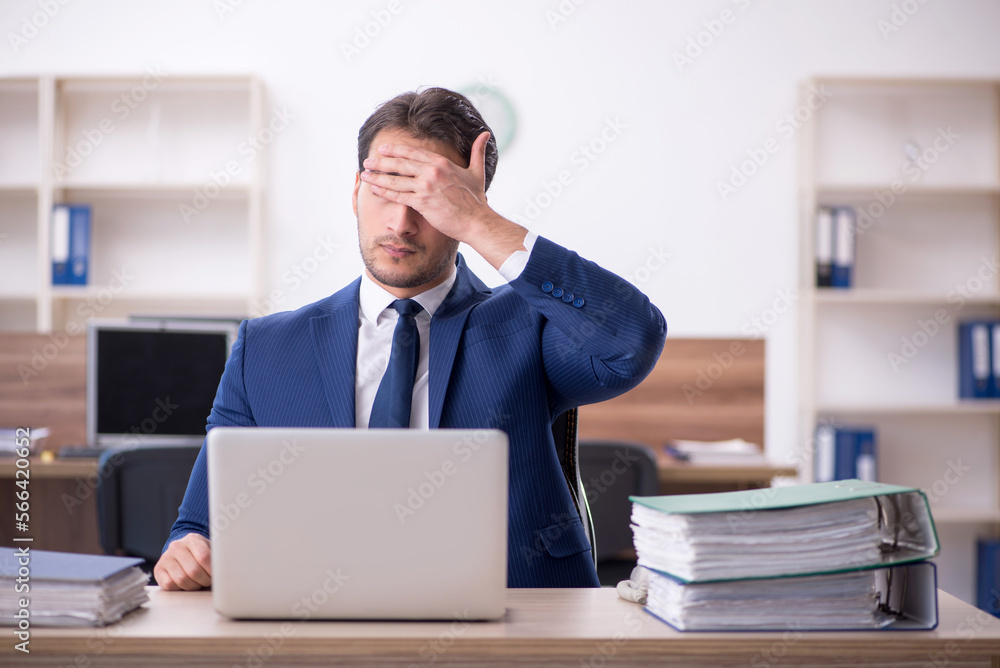 Young male employee and too much work in the office Young male employee and too much work in the office