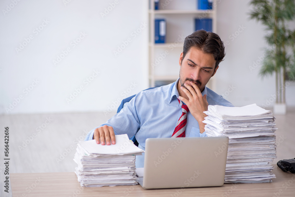 Young male employee and too much work in the office Young male employee and too much work in the office