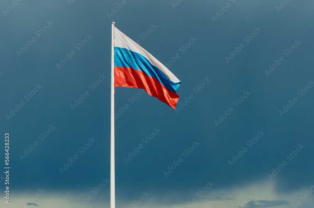 Russian flag against a dark blue sky with empty space for text. The state flag of the Russian Federation, 75 meters high, flutters in the wind. Built-in anemometer and emergency flag lowering system