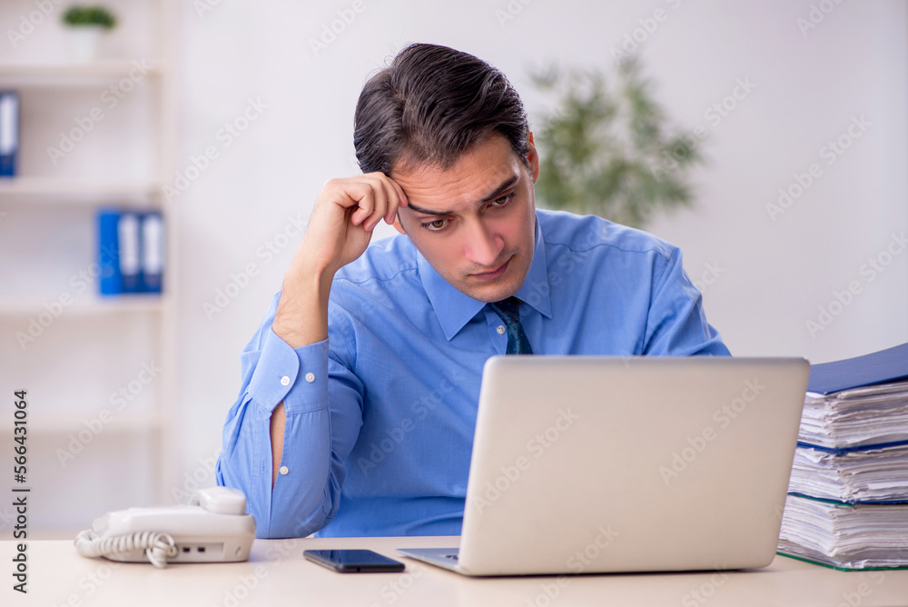 Young male employee and too much work in the office Young male employee and too much work in the office
