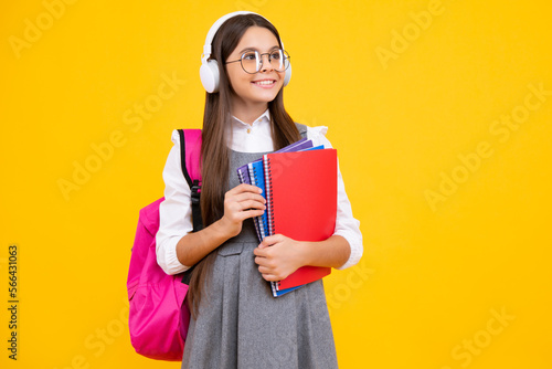 School girl, teenage student in headphones and books on isolated studio background. School kids with backpack. Happy face, positive and smiling emotions of teenager girl.