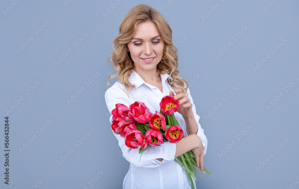 glad young woman with spring tulip flowers on grey background glad young woman with spring tulip flowers on grey background