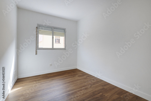 Bedroom of an empty house with a dark oak floor  white woodwork on the skirting boards and an aluminum window with shutters