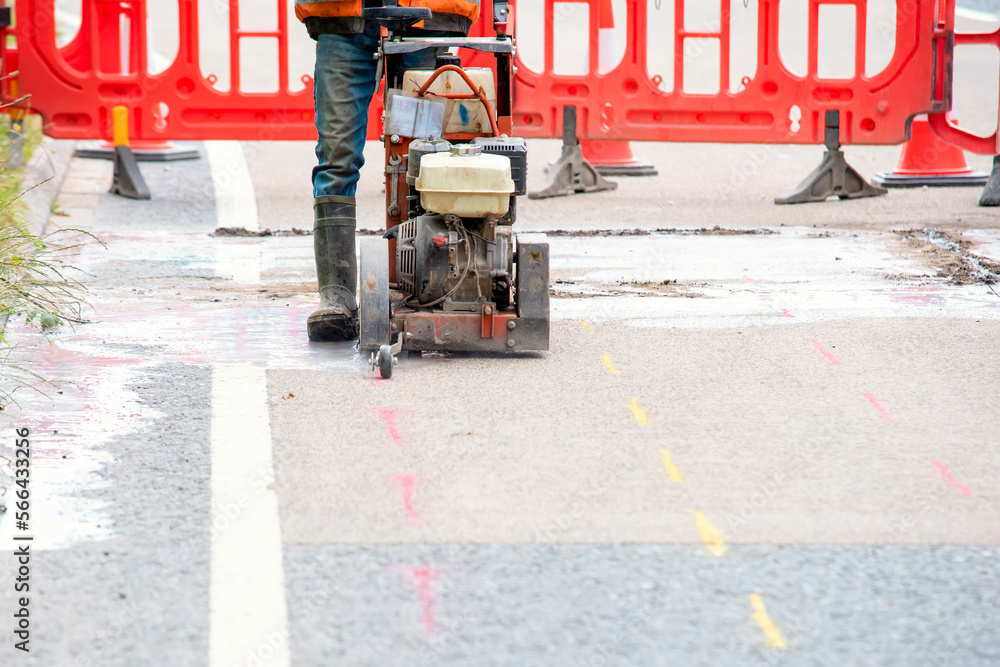 Builder using petrol powered road saw with dimond blade to cut asphalte road surface Builder using petrol powered road saw with dimond blade to cut asphalte road surface