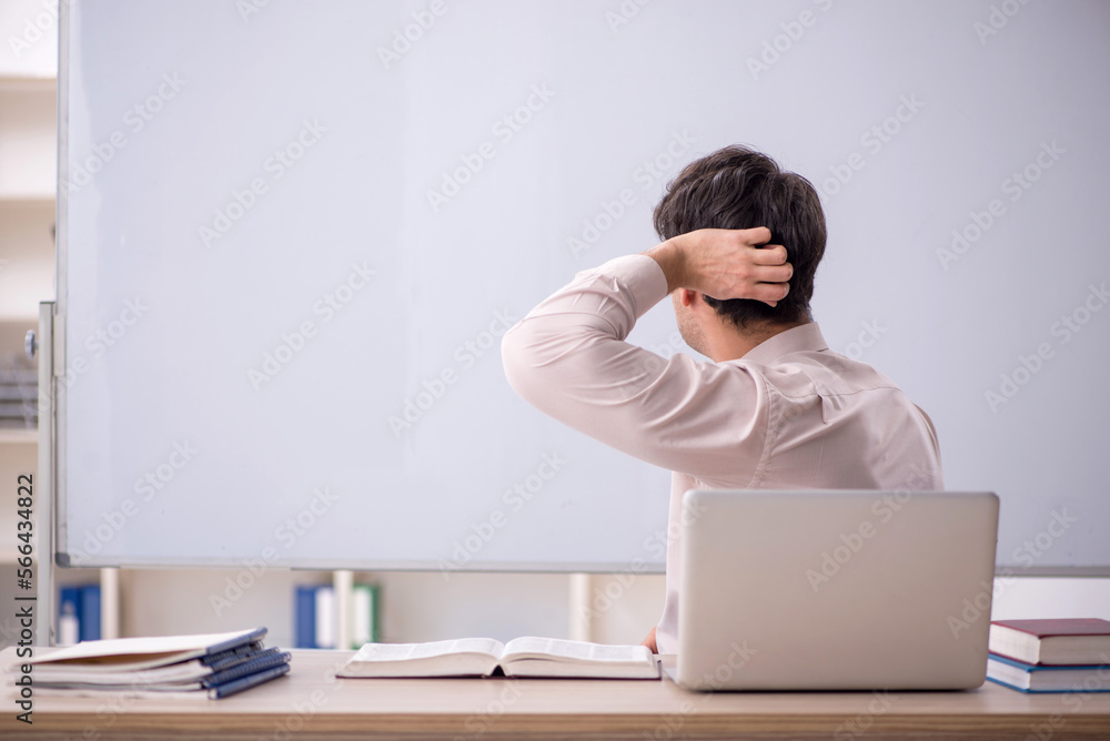 Young male teacher sitting in the classroom Young male teacher sitting in the classroom
