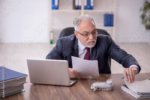 Old male employee and too much work in the office © Elnur