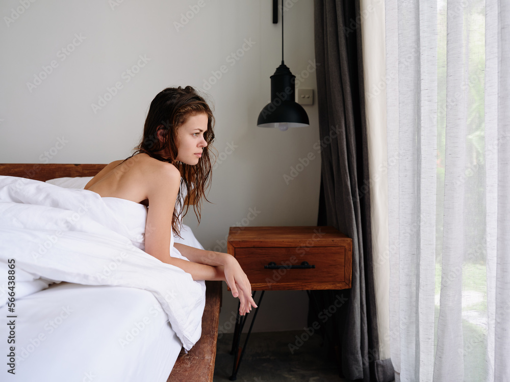A woman after a shower lies on a bed in a bedroom near a window with wet hair, a healthy sleep on an orthopedic patras and a memory foam pillow, body and hair care A woman after a shower lies on a bed in a bedroom near a window with wet hair, a healthy sleep on an orthopedic patras and a memory foam pillow, body and hair care