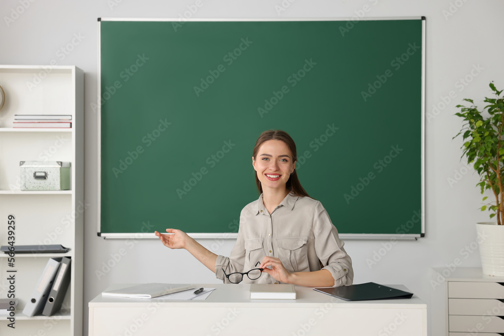 Beautiful young teacher giving lesson at table in classroom Beautiful young teacher giving lesson at table in classroom