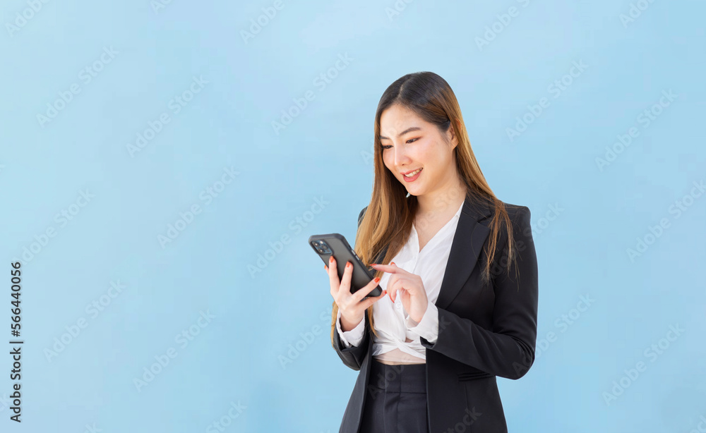 Asian businesswoman,Happy Asian woman texting on a phone standing isolated over blue background Asian businesswoman,Happy Asian woman texting on a phone standing isolated over blue background