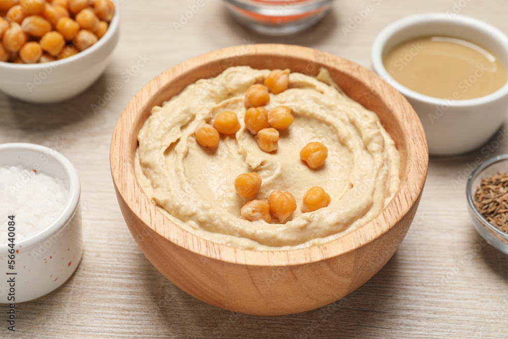 Bowl with delicious hummus and chickpeas on light wooden table, closeup Bowl with delicious hummus and chickpeas on light wooden table, closeup