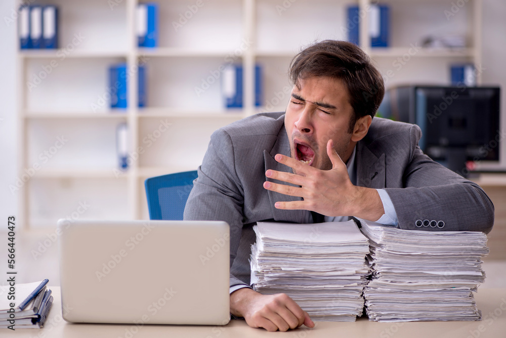 Young male employee and too much work in the office Young male employee and too much work in the office