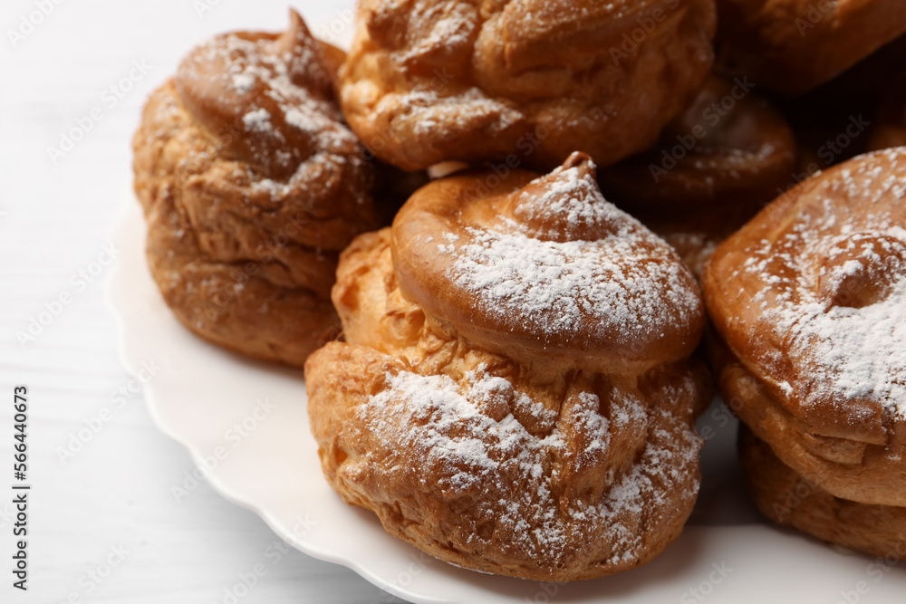 Delicious profiteroles with powdered sugar on white table, closeup Delicious profiteroles with powdered sugar on white table, closeup