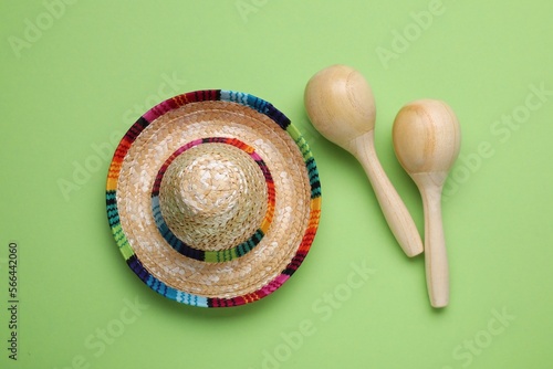 Colorful maracas and sombrero hat on light green background, flat lay. Musical instrument photo