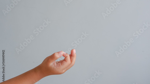 Young girl holding something on light grey background, closeup of hands. Copy space.