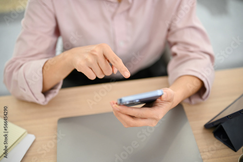 Top view of a female office worker using a smartphone at her desk, using mobile application