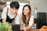 Happy young Asian couple enjoy baking in the kitchen together, having fun time together at home.