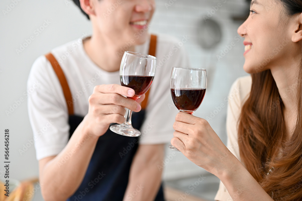 Close-up image of a lovely young Asian couple drinking wine while making dinner in the kitchen Close-up image of a lovely young Asian couple drinking wine while making dinner in the kitchen