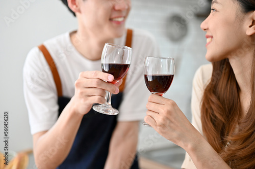 Close-up image of a lovely young Asian couple drinking wine while making dinner in the kitchen