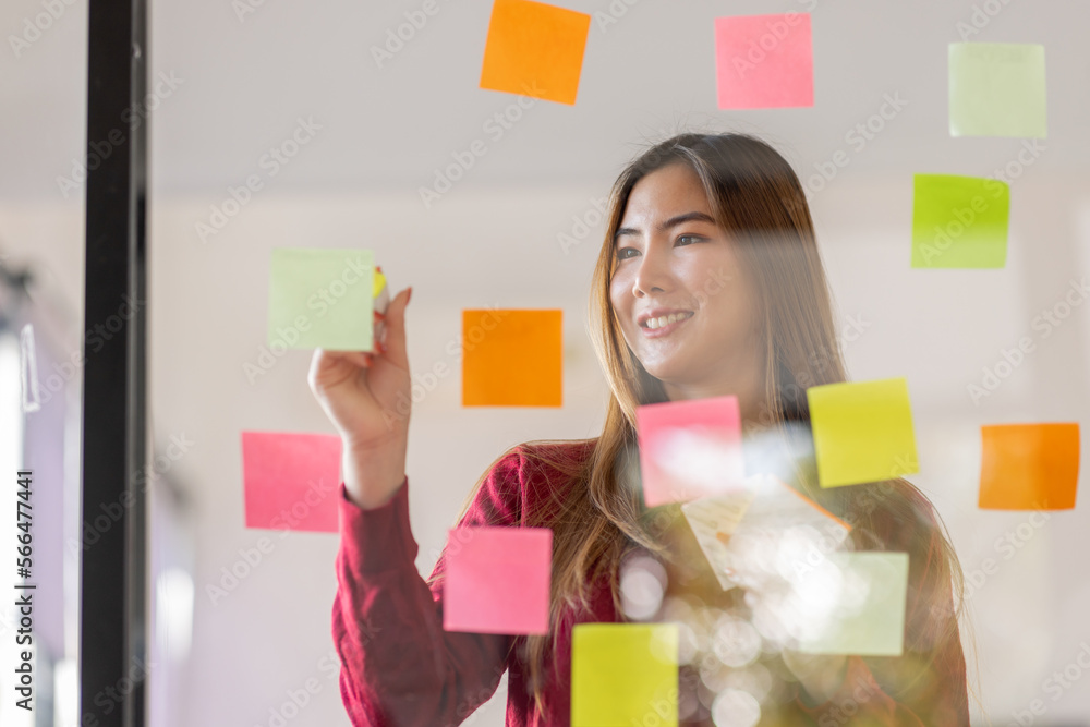 Asian businesswoman creating project plan on office wall with sticky paper notes. stylish confident manager working on business, financial and marketing planning projects. Asian businesswoman creating project plan on office wall with sticky paper notes. stylish confident manager working on business, financial and marketing planning projects.