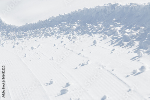 Long curved edge of winter snow on groomed ski slope background