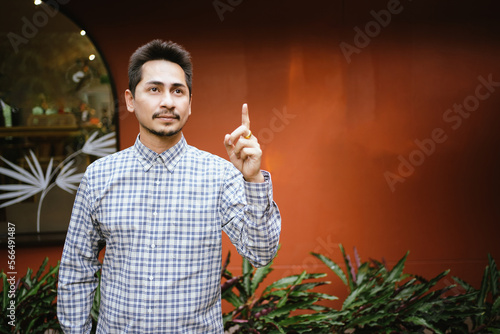 Young Muslim Raising the index finger for Tauhid symbol in islam on outdoor. photo