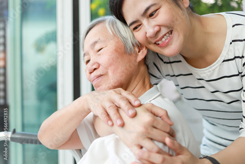 Happy female caregiver hugging old elderly woman from behind with tenderness and love,Asian adult daughter embraced her warmly at home,time spent together,family time,visiting the elderly,relationship