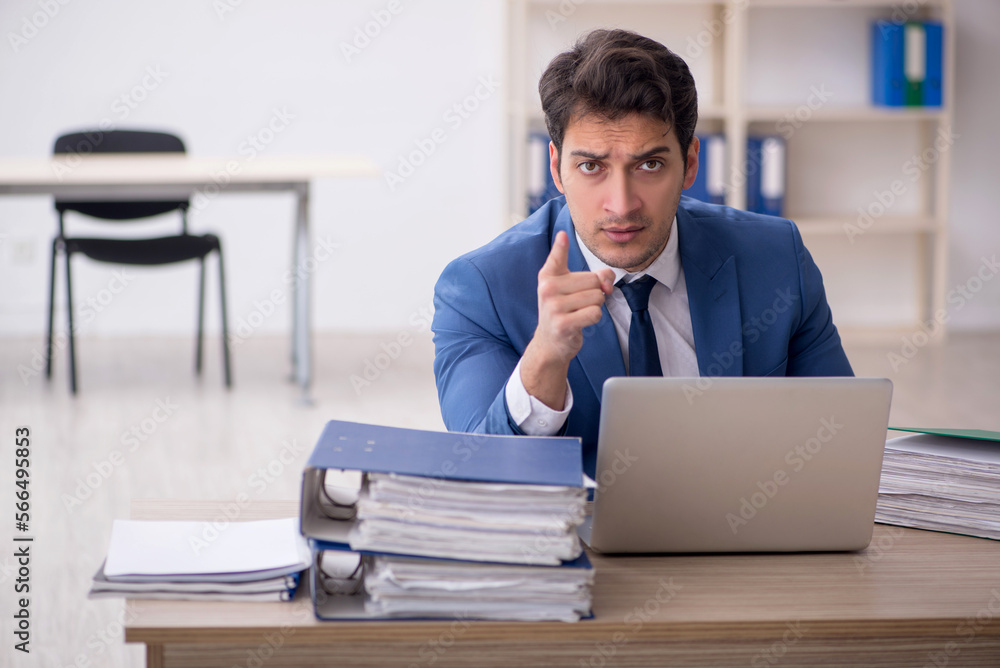 Young male employee and too much work in the office Young male employee and too much work in the office