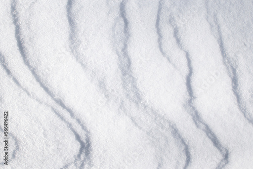 winter background with snowy ground. Wind sculpted patterns on snow surface.