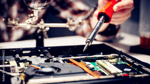 a computer master solders a chip and a board on a laptop, the concept of electronics repair shops