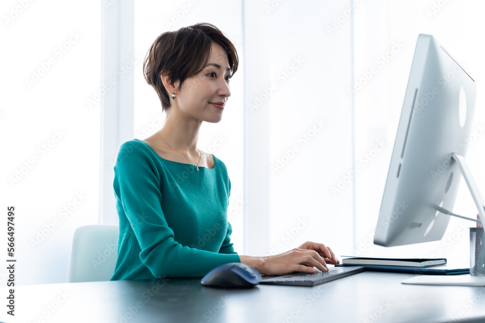 Obraz premium 綺麗な室内でパソコン作業をする私服のアジア人女性