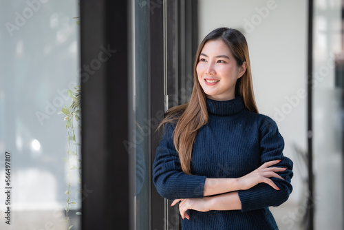 Confident Asian businesswoman standing with crossed arms and looking away.