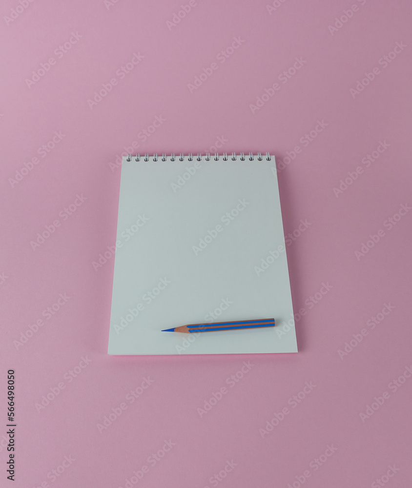 Spiral notebook with blue pencil on a pink background. Spiral notebook with blue pencil on a pink background.