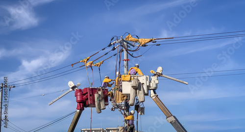 Electricians on crane working to fix power line