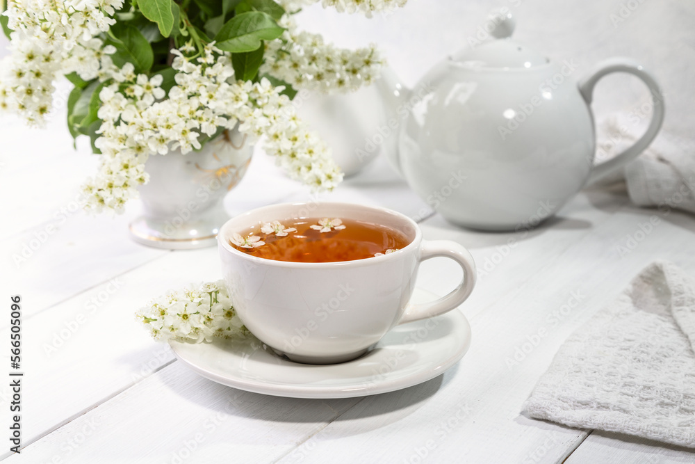 Useful spring tea with bird cherry in a white cup on a light background Useful spring tea with bird cherry in a white cup on a light background