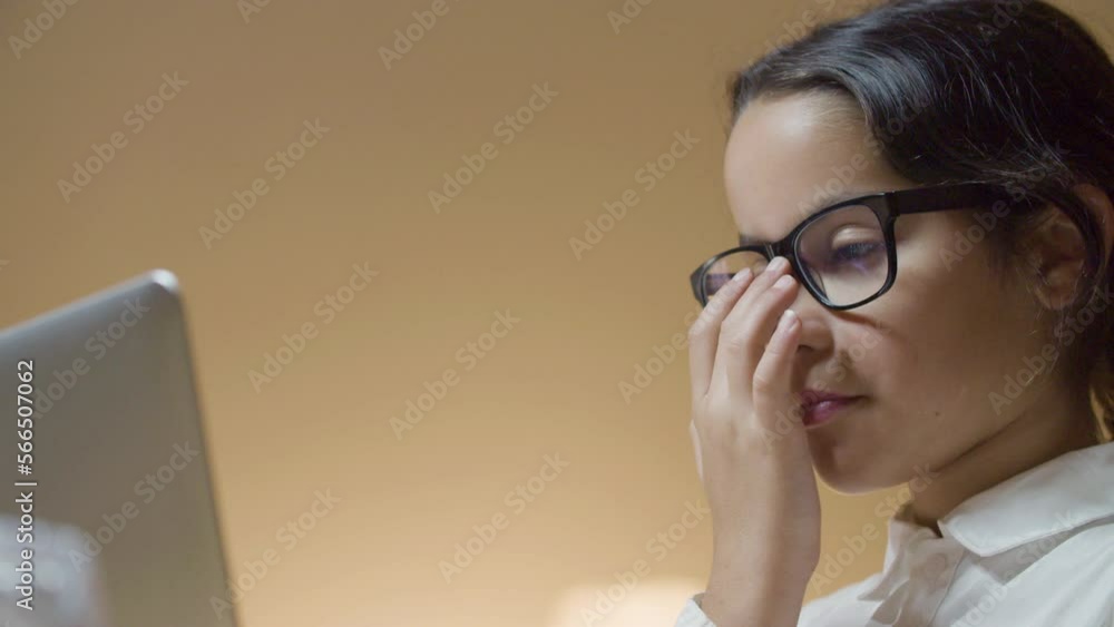 Low-angle shot of smart schoolgirl doing homework at home, working on computer. Serious young girl setting her glasses right, carrying on studying. Childhood, education concept Low-angle shot of smart schoolgirl doing homework at home, working on computer. Serious young girl setting her glasses right, carrying on studying. Childhood, education concept