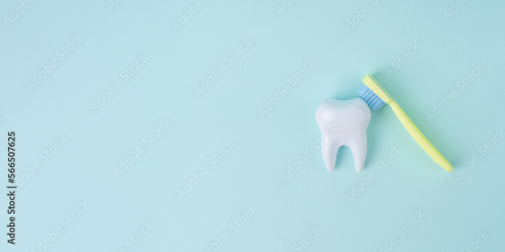 White tooth with a toothbrush on blue background with copy space. Dental health concept. Dentist day, National False Teeth Day. White tooth with a toothbrush on blue background with copy space. Dental health concept. Dentist day, National False Teeth Day.