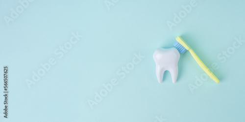 White tooth with a toothbrush on blue background with copy space. Dental health concept. Dentist day, National False Teeth Day.