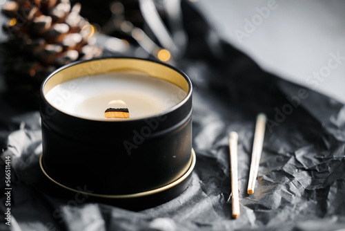 Soy scented candles in metal tins, boxes. Candles on the table in the room with a backdrop of pinecone and Christmas lights.  Modern handmade coconut wax candles without paraffin. burns Wooden wick. 