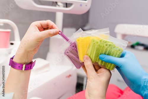 Ligature tie. Colorful rubber bands for bracket system, for braces. Close up of doctor hand in sterile glove holding colored orthodontic ligature tie. Concept of dentistry and orthodontics. photo