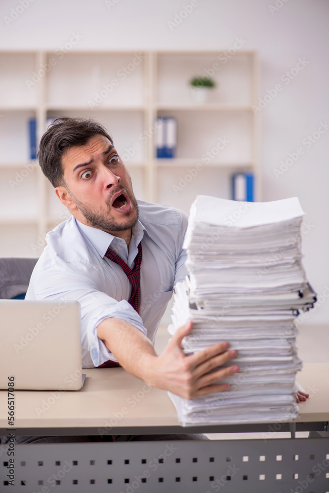 Obraz premium Young male employee unhappy with excessive work in the office