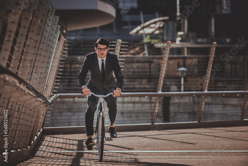 Young handsome man with business suit driving bicicyle to go to office - Corporate businessman portrait biking in the city, concepts about business, green mobility and lifestyle © oneinchpunch